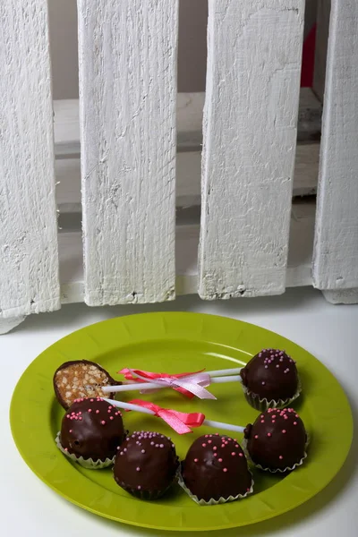 Pastel pops decorado con un lazo de trenza. Acuéstate en un plato. Junto a la caja de madera, pintada de blanco . — Foto de Stock