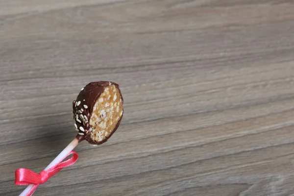 Cut cake pops. On a background with a woody texture. The candy is decorated with a ribbon bow.