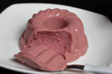 Lor jölesi. Tatlı bir tabakta, kaşıkta bir parça. Yakınlarda bir fincan kahve var..