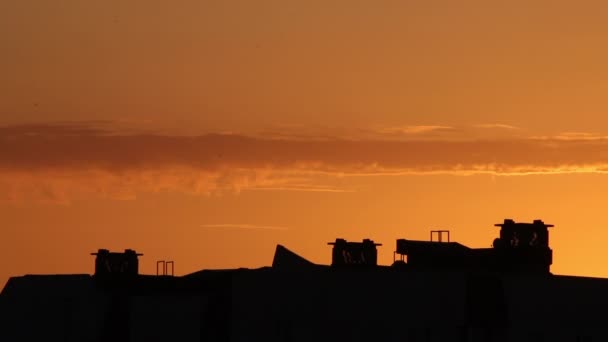 街の夕焼け明るいオレンジ色の空に雲が浮かぶ 都会の家の地平線上に見える屋上 — ストック動画