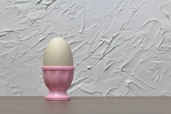Βραστό αυγό σε ροζ ποσέ. Στο φόντο του λευκού τοίχου με διακοσμητικό γύψο. — Φωτογραφία Αρχείου