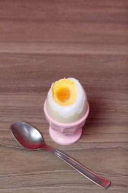 Haşlanmış pembe haşlanmış yumurta. Yemek için bir sonraki kaşık. Mercan renginin arka planına karşı.