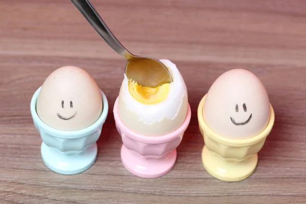 Een gekookt ei met een gehakte schil staat in een gepocheerde vorm. Op het ei geschilderde Smiley. Een lepel zit vast in het voor voedsel. — Stockfoto