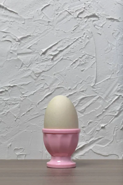 Βραστό αυγό σε ροζ ποσέ. Στο φόντο του λευκού τοίχου με διακοσμητικό γύψο. — Φωτογραφία Αρχείου