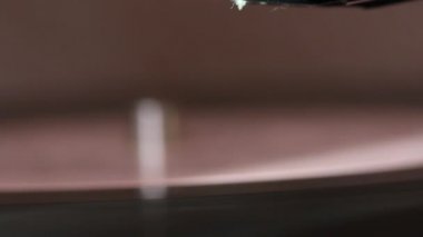 Vinil kayıt oyuncu üzerinde döner. Oyuncunun başı indirilir. İğne pistte. Her şey tozla kaplı..