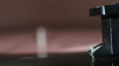 Vinil kayıt oyuncu üzerinde döner. Oyuncunun başı indirilir. İğne pistte. Her şey tozla kaplı..