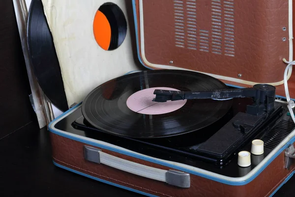 An old gramophone with a vinyl record mounted on it. Next to shabby paper envelopes are other records. — Stock Photo, Image