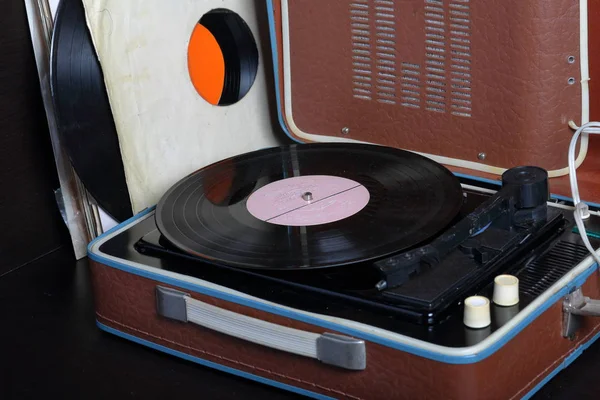 Ein altes Grammophon mit einer darauf montierten Schallplatte. Neben schäbigen Papierumschlägen liegen andere Platten. — Stockfoto