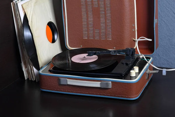 An old gramophone with a vinyl record mounted on it. Next to shabby paper envelopes are other records. — Stock Photo, Image