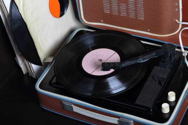 Un viejo gramófono con un disco de vinilo montado en él. Junto a sobres de papel de mala calidad hay otros registros . —  Fotos de Stock