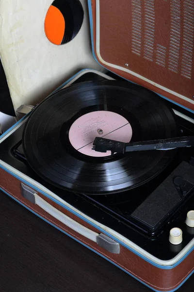 Un viejo gramófono con un disco de vinilo montado en él. Junto a sobres de papel de mala calidad hay otros registros . — Foto de Stock