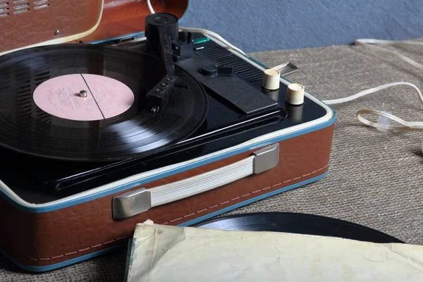 ビニールレコードが取り付けられた古い蓄音機。みすぼらしい紙の封筒の横には、他のレコードがあります. — ストック写真