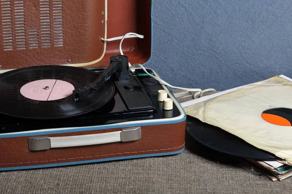 Um velho gramofone com um disco de vinil montado nele. Ao lado de envelopes de papel frágeis estão outros registros . — Fotografia de Stock