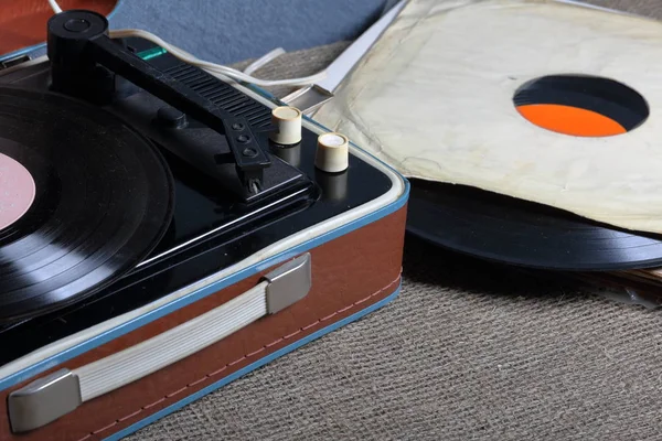 Um velho gramofone com um disco de vinil montado nele. Ao lado de envelopes de papel frágeis estão outros registros . — Fotografia de Stock