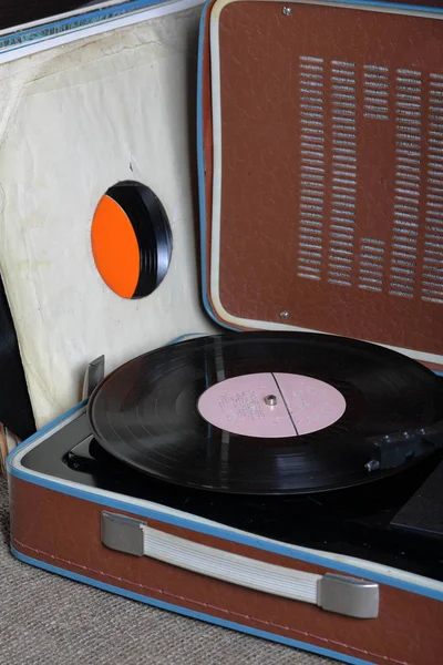 Un viejo gramófono con un disco de vinilo montado en él. Junto a sobres de papel de mala calidad hay otros registros . — Foto de Stock