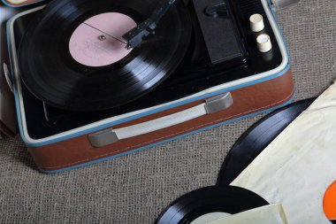 Üzerinde vinil plak olan eski bir gramofon. Eski püsha kağıt zarfların yanında diğer kayıtlar var..