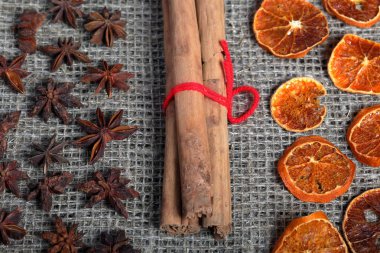 Kurutulmuş portakal dilimleri, tarçın ve dekorasyon için anason. Kaba keten kumaş üzerine serilmiş