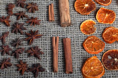 Kurutulmuş portakal dilimleri, tarçın ve dekorasyon için anason. Kaba keten kumaş üzerine serilmiş
