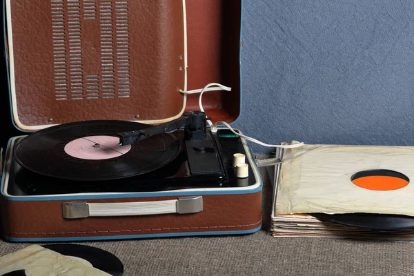 Un viejo gramófono con un disco de vinilo montado en él. Junto a sobres de papel de mala calidad hay otros registros . — Foto de Stock