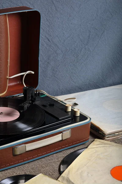 Um velho gramofone com um disco de vinil montado nele. Ao lado de envelopes de papel frágeis estão outros registros . — Fotografia de Stock