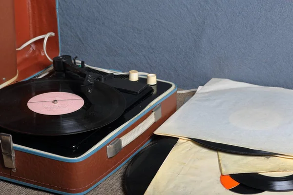 Un viejo gramófono con un disco de vinilo montado en él. Junto a sobres de papel de mala calidad hay otros registros . — Foto de Stock