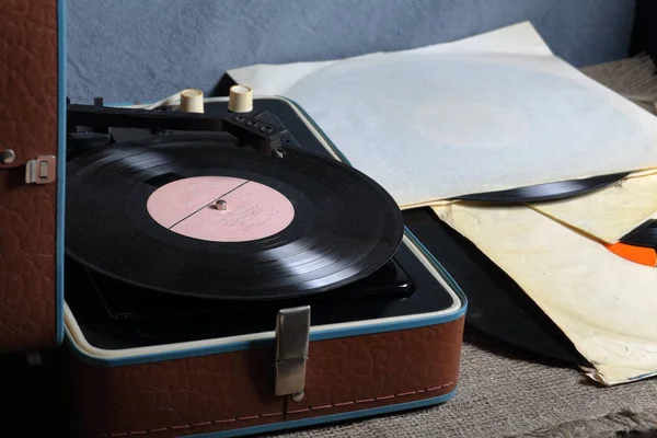 Un viejo gramófono con un disco de vinilo montado en él. Junto a sobres de papel de mala calidad hay otros registros . —  Fotos de Stock