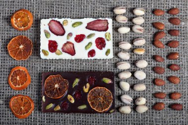 Kurutulmuş portakal dilimleri, antep fıstığı ve badem kaba keten kumaş dizilir. Kurutulmuş meyve ile süslenmiş koyu ve beyaz çikolata.