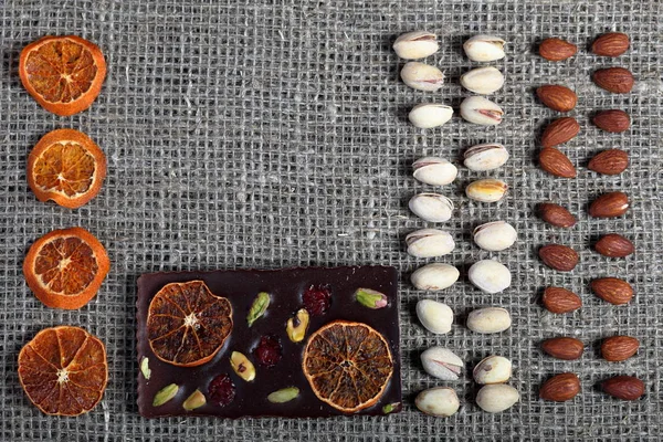 Dried orange slices, pistachios and almonds are laid out in rows on coarse linen fabric.