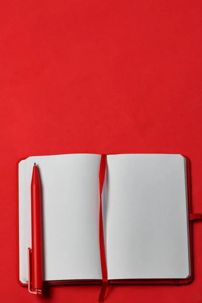 Carnet de notes sur la couverture rouge. Avec un signet rouge et un stylo. Les mensonges s'ouvrent sur un fond de corail. Fournitures scolaires . — Photo