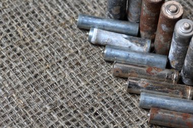 Harcanan piller kaba bir keten arka plan üzerinde yatıyor. Korozyonla kaplı. Geri dönüşüm ve çevre koruma.