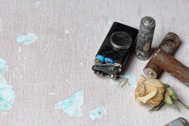 Harcanan piller boya soyma ile yüzeyde uzanır. Korozyonla kaplı. Yakınlarda sedilmiş bir gül var. Geri dönüşüm ve çevre koruma.