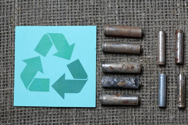 Les piles usagées se trouvent sur la surface avec de la peinture pelante. Recouvert de corrosion. A proximité se trouve le panneau de recyclage. Recyclage et protection de l'environnement . — Photo