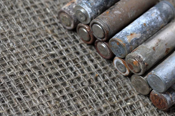 Förbrukade batterier ligger på en grov linne bakgrund. Täckt med korrosion. Återvinning och miljöskydd. — Stockfoto