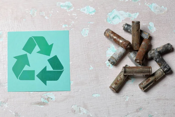 Baterias passadas jazem na superfície com tinta descascada. Coberto de corrosão. Perto está o sinal de reciclagem. Reciclagem e protecção do ambiente . — Fotografia de Stock