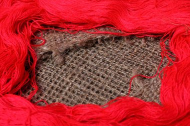 Kaba keten kumaş. Üzerinde kırmızı iplikler hanks vardır.