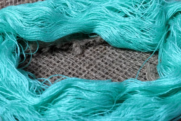 Tejido de lino grueso. En ella están las madejas de hilos verdes . —  Fotos de Stock