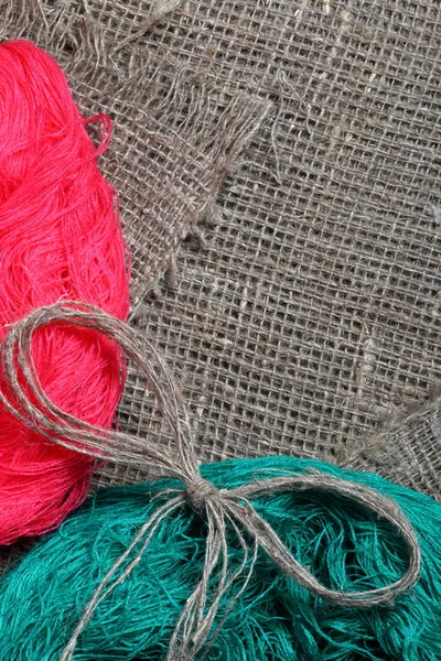 Tejido de lino grueso. En ella están las madejas de hilos de colores. Sobre ella yace un arco de hilo de lino . —  Fotos de Stock