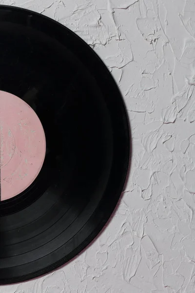 Old vinyl record. Worn and dirty. It lies on the surface covered with decorative plaster.