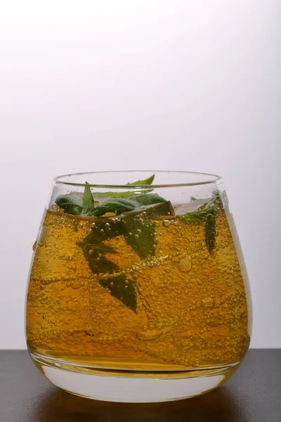 Refreshing drink with gas bubbles. Nalit in a transparent glass. It laid crushed ice. Decorated with mint leaves. — Stock Photo, Image