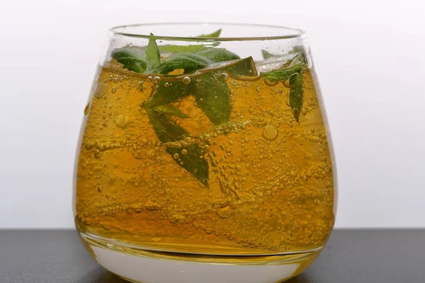 Refreshing drink with gas bubbles. Nalit in a transparent glass. It laid crushed ice. Decorated with mint leaves. — Stock Photo, Image