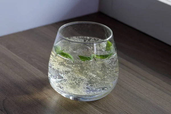 Refreshing drink with gas bubbles. Nalit in a transparent glass. It laid crushed ice. Decorated with mint leaves.