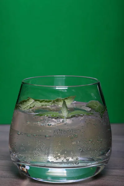 Refreshing drink with gas bubbles. Nalit in a transparent glass. It laid crushed ice. Decorated with mint leaves.