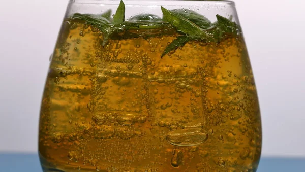 Bevanda rinfrescante con bolle di gas. Nalit in vetro trasparente. Ha posato il ghiaccio tritato. Decorato con foglie di menta . — Foto Stock