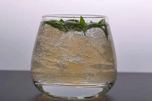 Refreshing drink with gas bubbles. Nalit in a transparent glass. It laid crushed ice. Decorated with mint leaves. — Stock Photo, Image