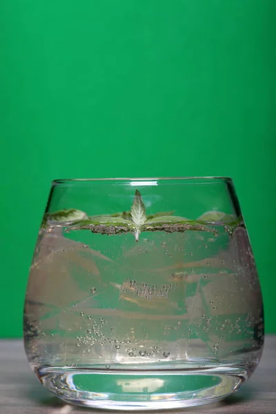 Bebida refrescante con burbujas de gas. Nalit en un vaso transparente. Echaba hielo picado. Decorado con hojas de menta . — Foto de Stock