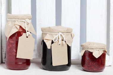 Reçel kavanozları, kağıt ile kaplıdır ve ikiyle bağlanmış. Dize asmak Craft etiketleri. Ahşap tahtaları arka planda.