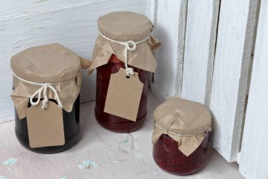 Reçel kavanozları, kağıt ile kaplıdır ve ikiyle bağlanmış. Dize asmak Craft etiketleri. Ahşap tahtaları arka planda.