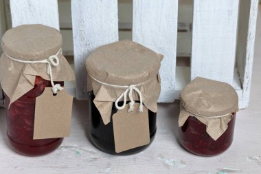 Reçel kavanozları, kağıt ile kaplıdır ve ikiyle bağlanmış. Dize asmak Craft etiketleri. Ahşap tahtaları arka planda.
