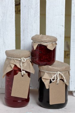 Reçel kavanozları, kağıt ile kaplıdır ve ikiyle bağlanmış. Dize asmak Craft etiketleri. Ahşap tahtaları arka planda.