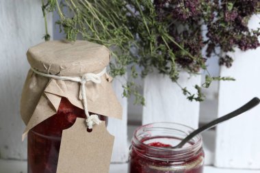 Reçel kavanozları, kağıt ile kaplıdır ve ikiyle bağlanmış. Dize asmak Craft etiketleri. Yeşil ve baharatların Tufts yakınında. Ahşap tahtaları arka planda.